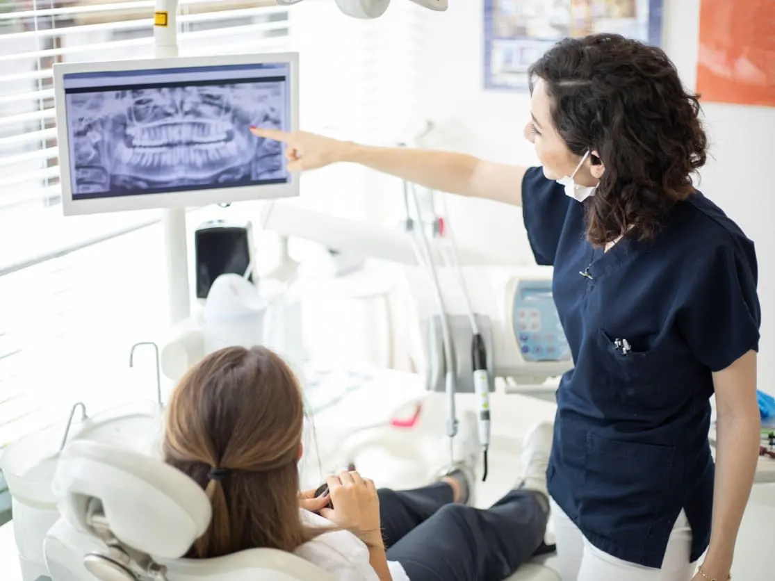 Dentysta pokazuje pacjentowi RTG jego szczęki i zębów.