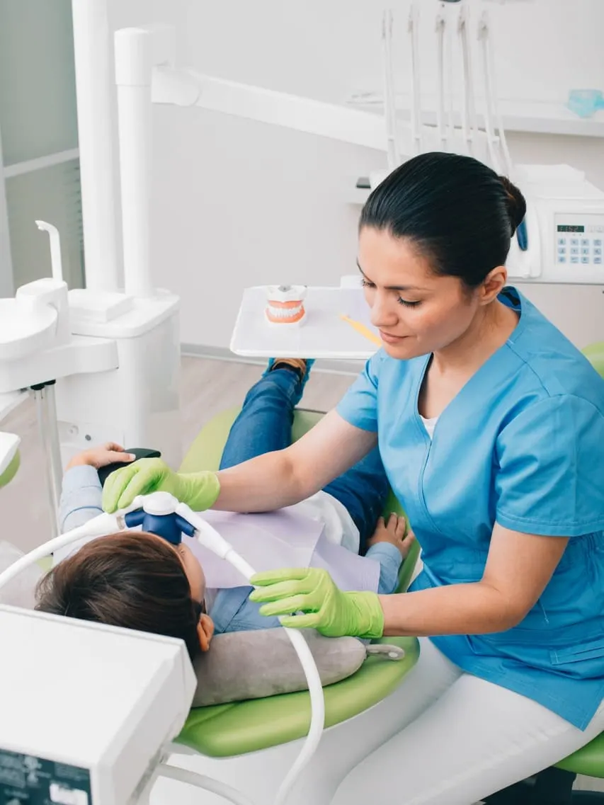 Dentysta przeprowadza sedację wziewną małemu dziecku.