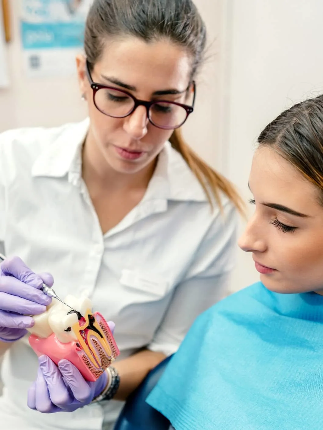 Dentysta pokazuje pacjentowi model uzębienia z rozwiniętą próchnicą.